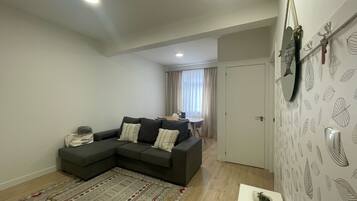 A modern living room with a sectional sofa, a patterned rug, and a dining area in the background.