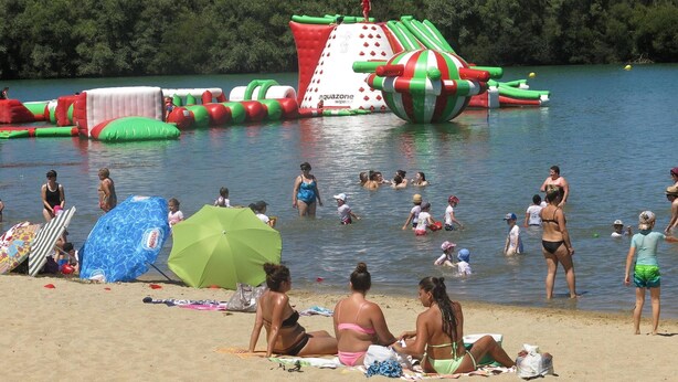 A beach with inflatable water structures and people enjoying the water.