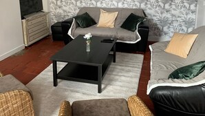A living room with a sofa, two armchairs, a coffee table, and a television.