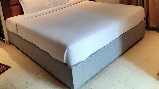 A large bed with a wooden headboard, a bedside table, and a nightstand.