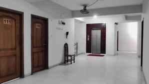 A hallway with wooden doors numbered 111 and 110, a chair, a red mat, and an elevator.