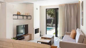 Een moderne woonkamer met een flatscreen televisie, een open haard, een bank, een salontafel en een schuifdeur naar een buitenruimte.