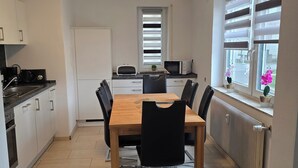 Een moderne keuken met een eettafel, stoelen en een raam met jaloezieën.