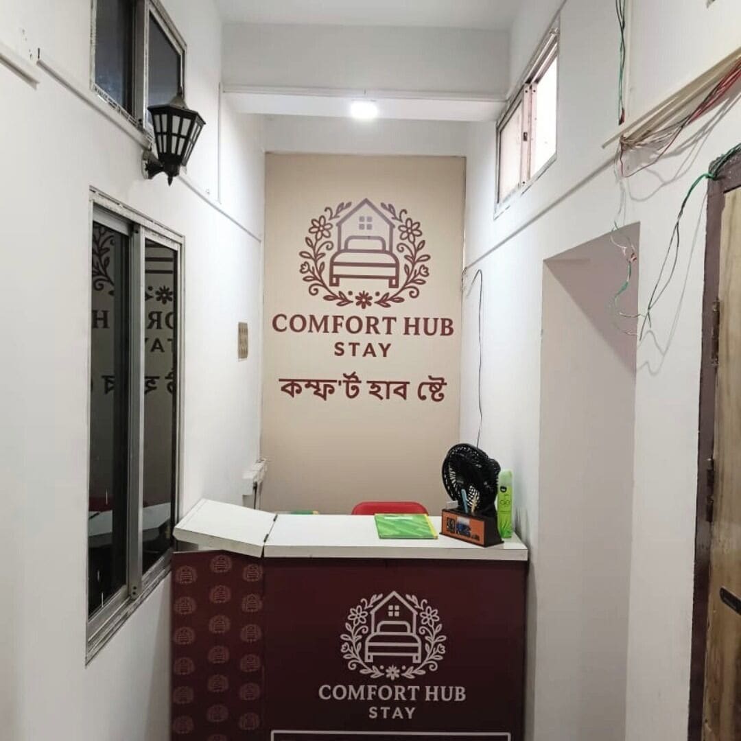 Un couloir étroit avec un comptoir d’accueil portant l’inscription « COMFORT HUB STAY » et un panneau mural affichant le même texte.