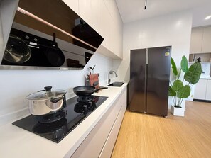 Et moderne køkken med et indbygget komfur, et rustfrit stål køleskab og en stor potteplante.