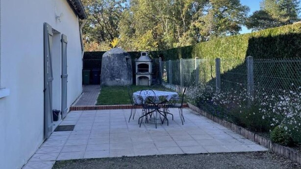 A patio with a table and chairs, a stone structure, and a fence. - Stay at the edge of Chambord Park, comfy former lodging close to windmills (Maslives)