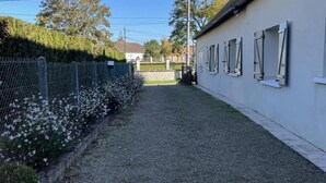A narrow pathway leading to a building with a white exterior and multiple windows. - Stay at the edge of Chambord Park, comfy former lodging close to windmills (Maslives)