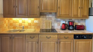 A kitchen with wooden cabinets, a sink, a stove, and a coffee maker. - Stay at the edge of Chambord Park, comfy former lodging close to windmills (Maslives)