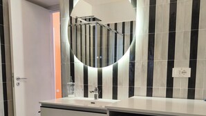 Ein modernes Badezimmer mit einem schwarz-weißen Schachfußboden, einem weißen Waschbecken mit Glas und einer Candy Rapid Waschmaschine.