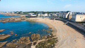 Une ville côtière dotée d’une plage de sable, d’une côte rocheuse et de bâtiments situés le long du rivage.
