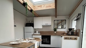 Une cuisine compacte dotée d’un puits de lumière, d’un plancher en bois et de meubles blancs.