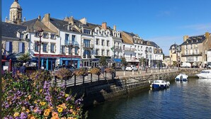 Une promenade en bord de mer bordée de bâtiments historiques, d’un pont de pierre et de bateaux amarrés le long du quai.