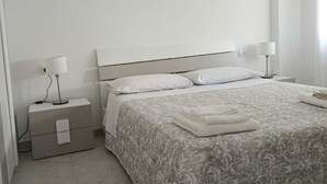 A minimalist bedroom with a bed, nightstands, and a lamp.