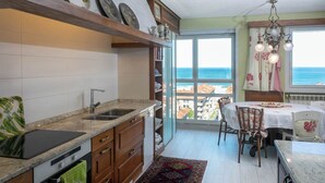 A kitchen with a view of the sea, wooden cabinets, a sink, and a dining area with a table and chairs.