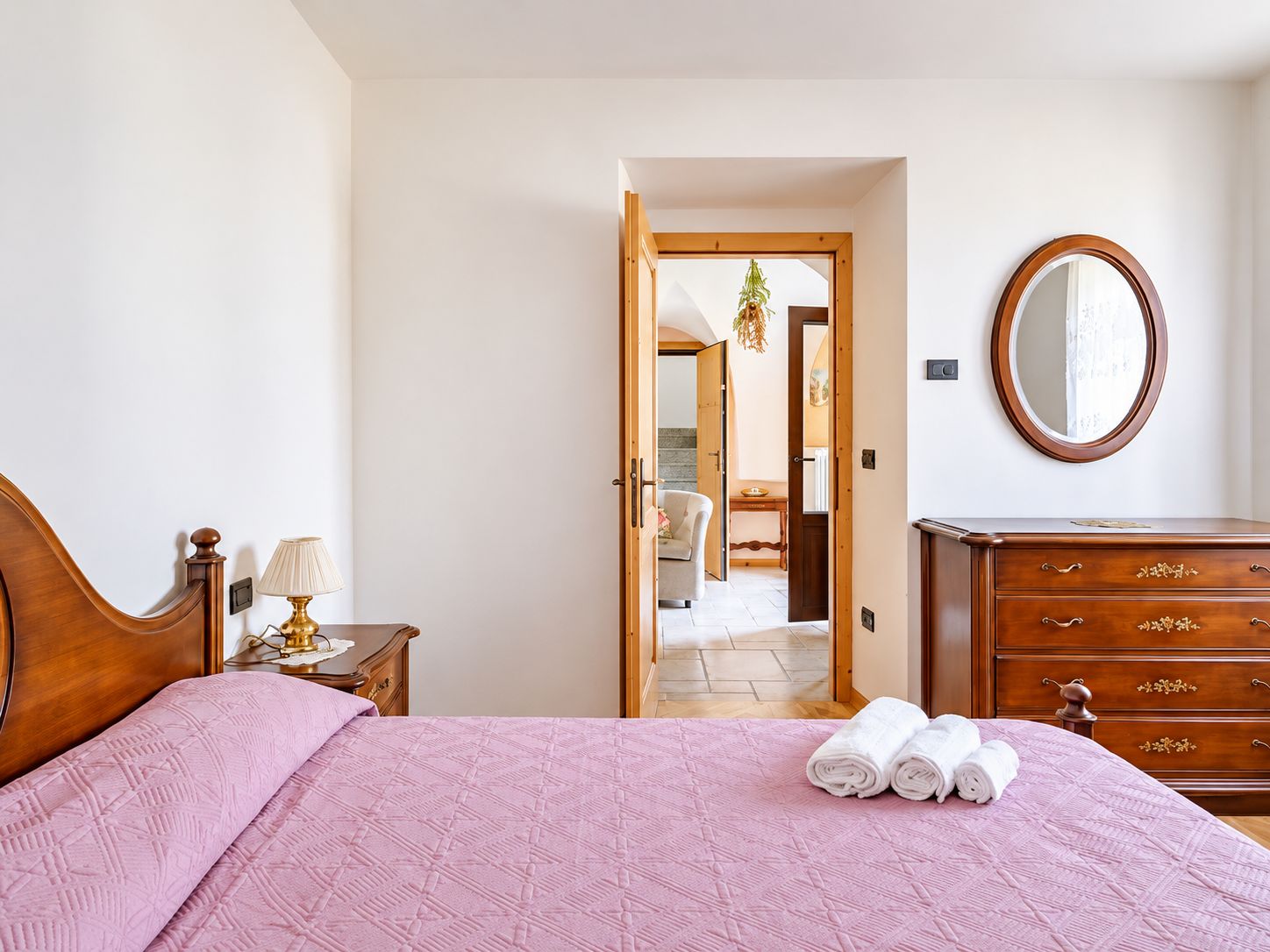 A bedroom with a bed, a dresser, a mirror, and a door leading to another room.