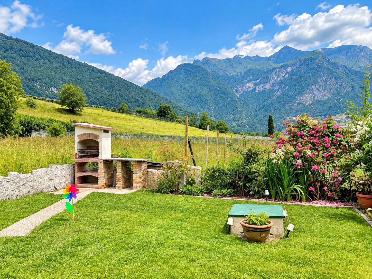 A garden with a barbecue area, a flower bed, and a view of mountains.