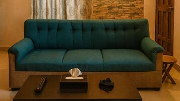 Ein türkisfarbenes Sofa in einem Wohnzimmer mit Fernbedienung und Taschentüchern auf einem Couchtisch.
