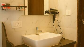 A bathroom with a white sink, a mirror, a hairdryer, and two towels hanging on towel bars.
