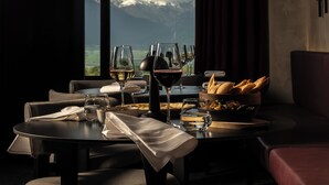 A dining table set with wine glasses, a bowl of bread, and a view of mountains. - The Wine Station (Tsinandali)