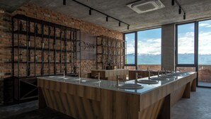 A bar area with a long wooden counter, multiple sinks, and a brick wall with shelves displaying bottles. - The Wine Station (Tsinandali)
