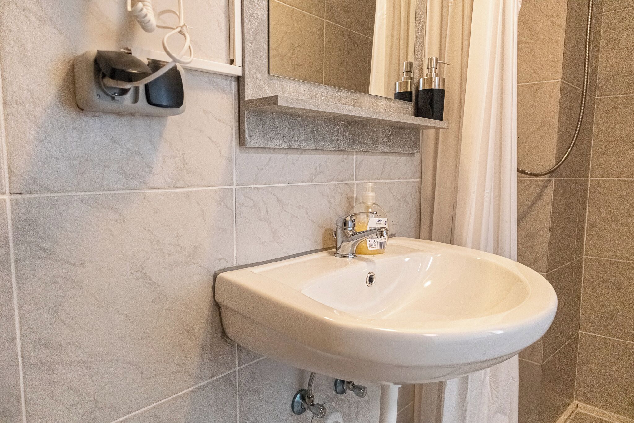 Un baño con lavamanos blanco, un espejo y ducha.