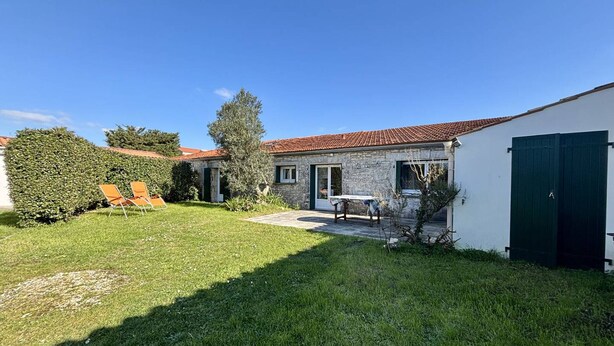 Ein Haus aus Stein mit Ziegeldach, einer grünen Tür und einem kleinen Garten mit Rasen und Hecke.