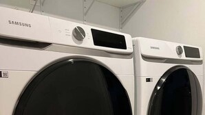 Dos lavadoras Samsung de carga frontal en una sala de exposición con piso de baldosas.