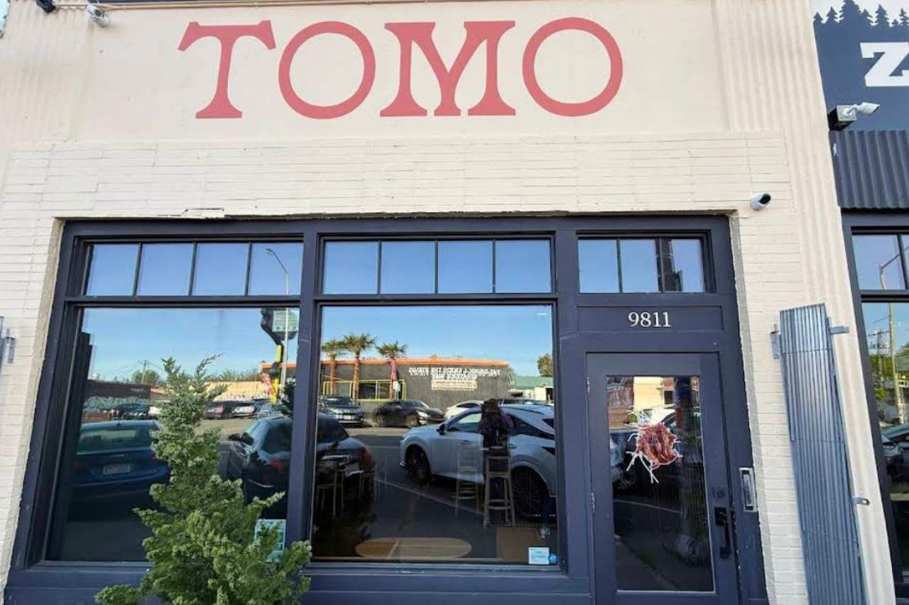 The exterior of a building with the name 'TOMO' in large letters above the entrance.