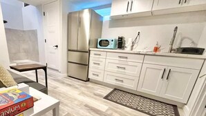 Una cocina moderna con gabinetes blancos, un refrigerador de acero inoxidable, un microondas y un lavabo.