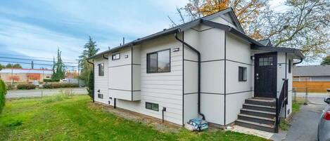 Une maison mobile de plain-pied avec une porte d’entrée noire, un petit porche à l’avant et une porte de garage visible.