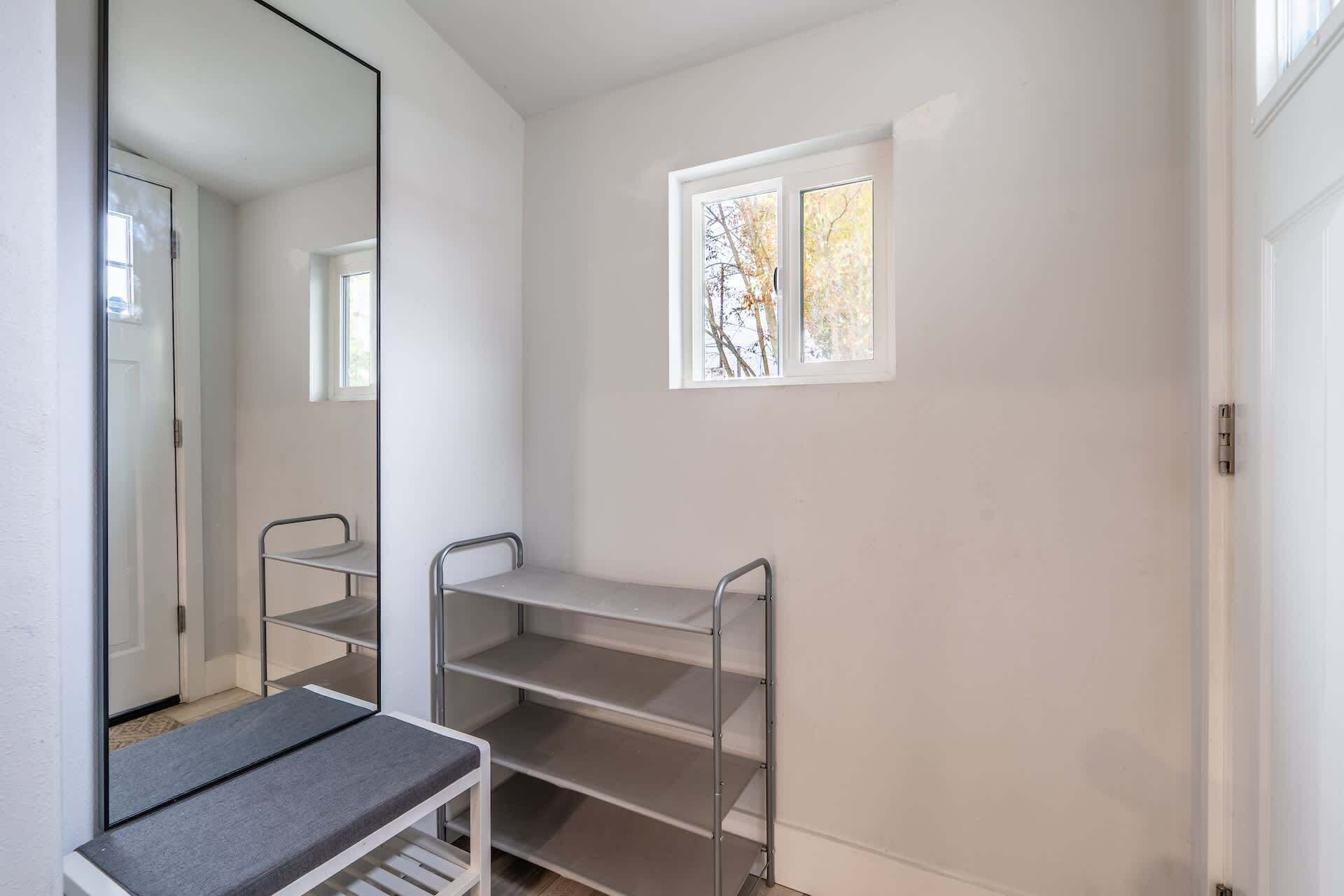 Ein kleiner, heller Raum mit Fenster, einem Spiegel und Metallregalen.