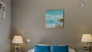 A hotel room with a bed, two nightstands, a painting of a beach, and a white bird decoration. - Bright house 9 pers, beach access, parking, Sarzeau (Sarzeau)