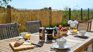 A wooden table set for breakfast with a coffee maker, a fruit bowl, and a glass of orange juice. - Bright house 9 pers, beach access, parking, Sarzeau (Sarzeau)