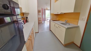 A compact kitchen with a built-in oven, a sink, and wooden cabinets.
