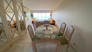 Zona pranzo con un tavolo rotondo in vetro, sei sedie in vimini e una ventola a soffitto.