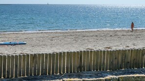 A beach with a wooden fence, a surfboard, and a person standing on the sand. - Holiday home 4 ppl - Sea view & beach access - Sarzeau (Sarzeau)
