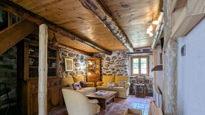 A rustic cabin interior with stone walls, wooden beams, a stone fireplace, and a cozy seating area with a sofa and armchairs. - Renovated cottage for 4 pers. with equine accommodation, Saint-Front (Saint-Front)