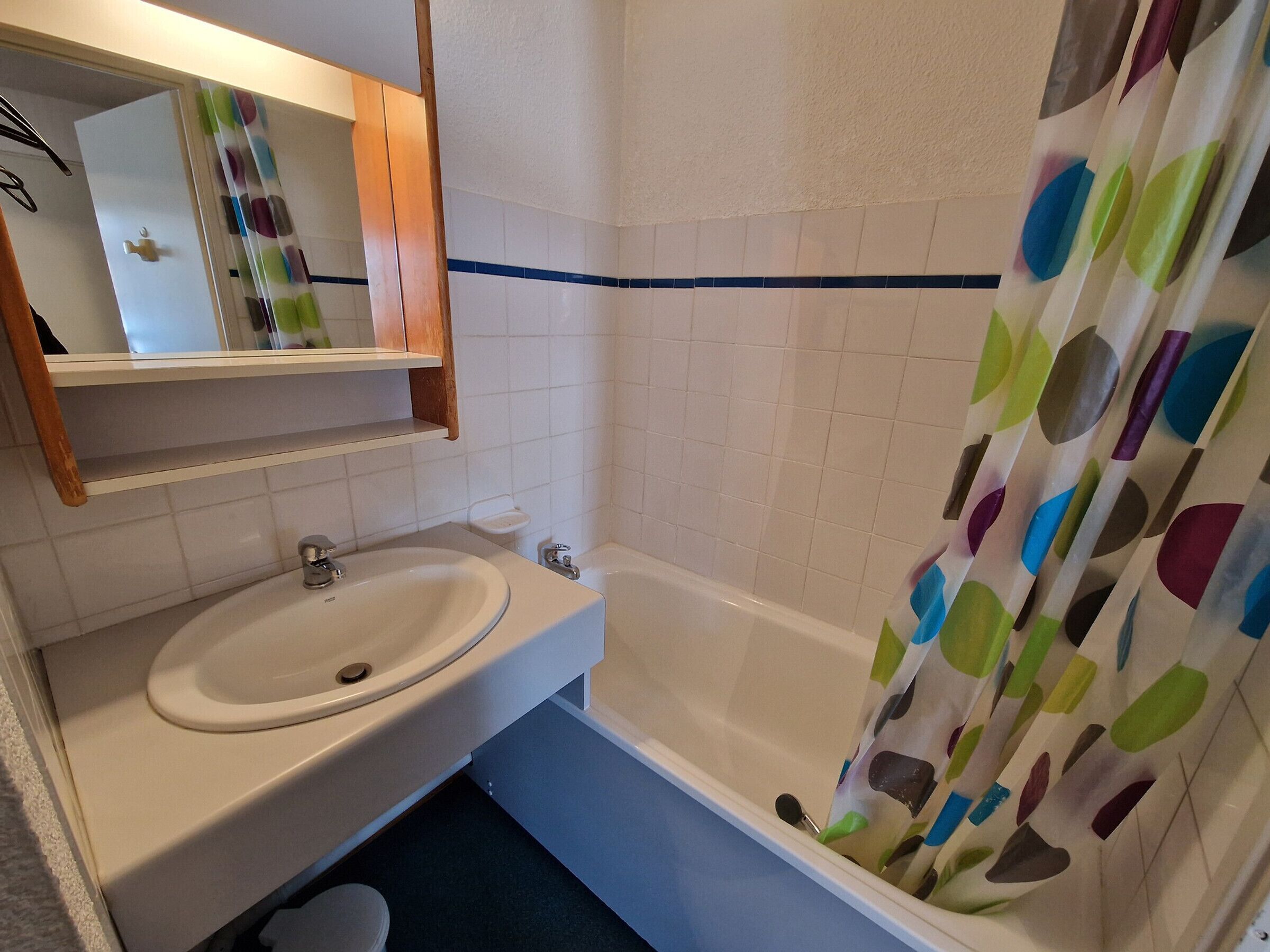 A bathroom with a white sink, mirror, and bathtub.