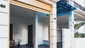 A modern building entrance with a covered porch, a staircase, and a view of the surrounding area.