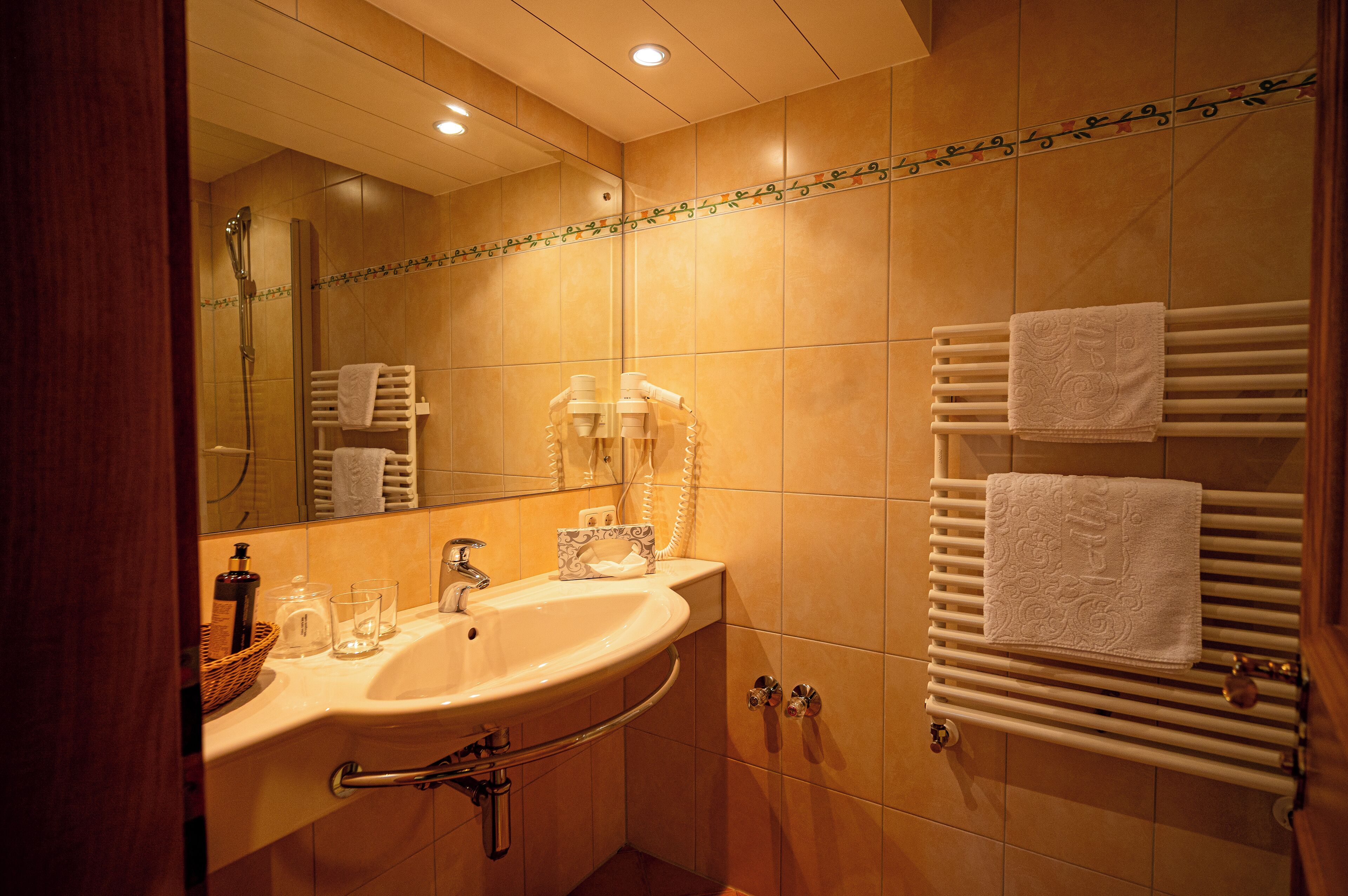 A bathroom with a sink, mirror, towel rack, and shower.