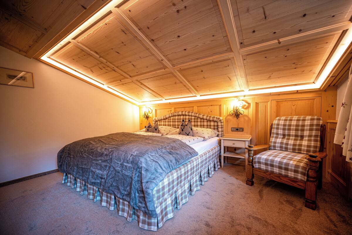 A bedroom with a bed, a chair, and a nightstand.
