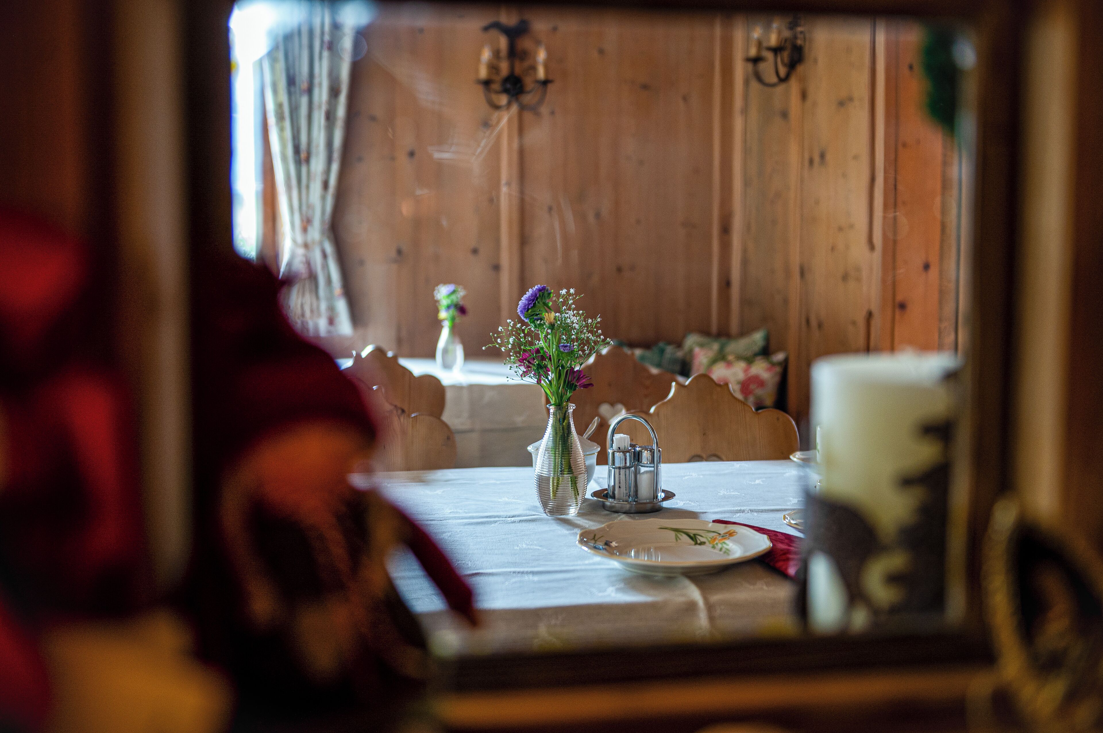A dining table with a vase of flowers, a salt shaker, and a plate.