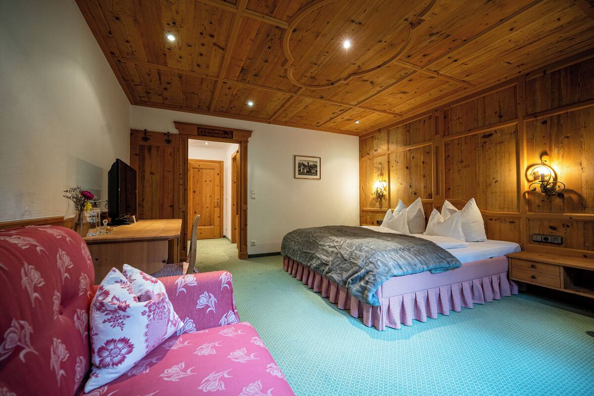 A wooden-paneled room with a bed, a sofa, and a desk.