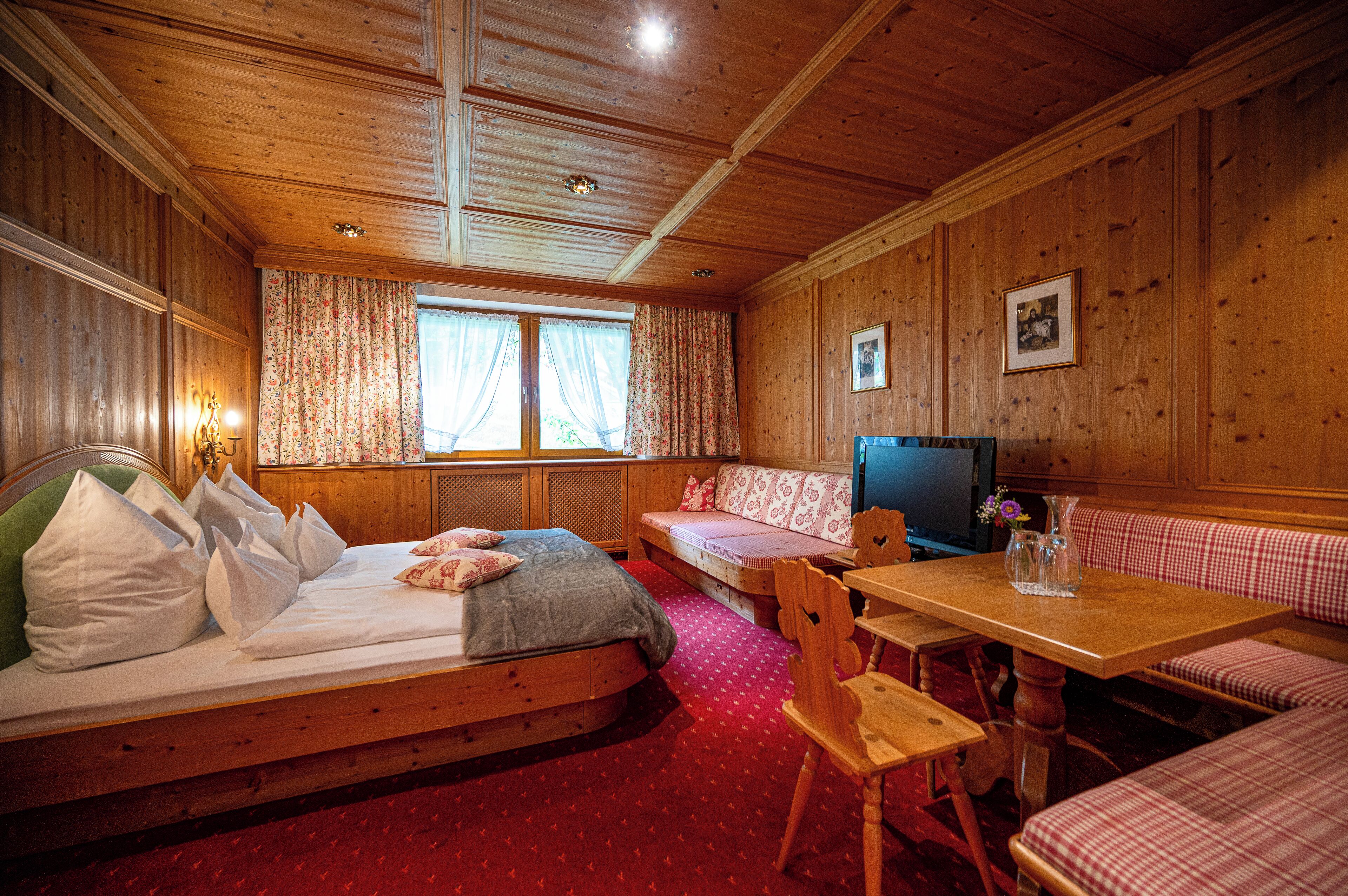 Una cabaña de madera con una cama, un banco, una mesa y un televisor.