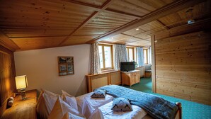 Una habitación con paneles de madera, una cama, un escritorio, un televisor y una ventana con cortinas.