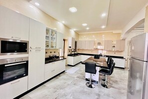 A modern kitchen with built-in appliances, a central island with bar stools, and a large window providing natural light.