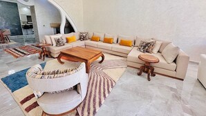 A spacious living room with a large L-shaped sofa, a round armchair, and a wooden coffee table.
