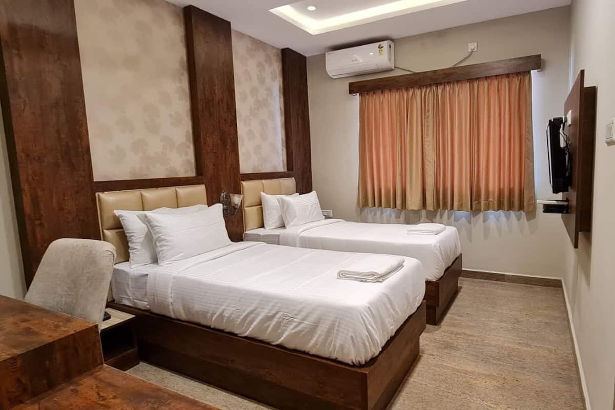 Ein Hotelzimmer mit zwei Betten, einem Schreibtisch, einem Sessel und einem Fernseher.