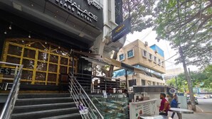 A hotel entrance with a staircase leading to the lobby, a glass display case, and a sign for a restaurant. - Stayz Royale Koramangala (Bengaluru)