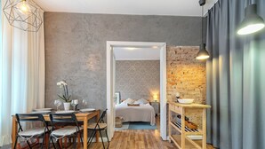 Una habitación moderna con una mesa de madera, sillas, una cama y una mesita con un bol.